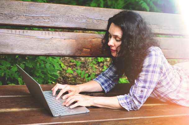 Подорожуюча жінка використовує ноутбук у парку. Концепція позаштатної роботи у подорожах по природі
 - Фото, зображення
