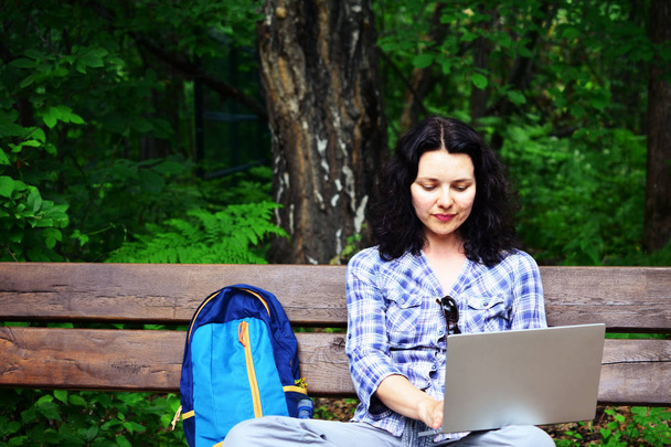 Vrouw met laptop in park te reizen. Concept van freelance werken in reizen werken op aard - Foto, afbeelding