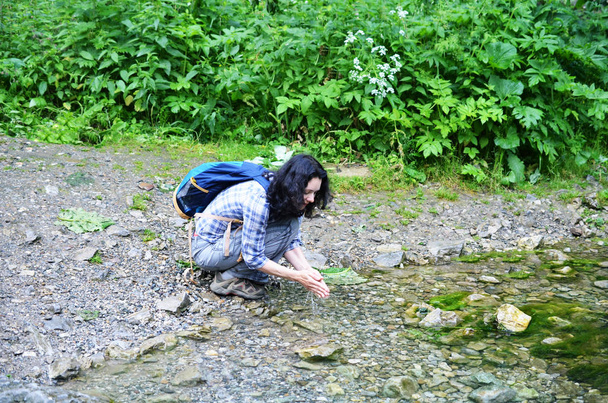 Femme voyageuse buvant de l'eau pure d'un ruisseau forestier frais
 - Photo, image