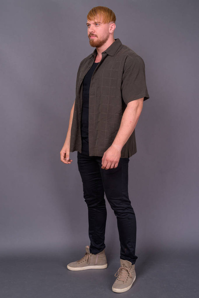 Studio shot of bearded man with blond hair wearing casual clothes against gray background - Photo, Image
