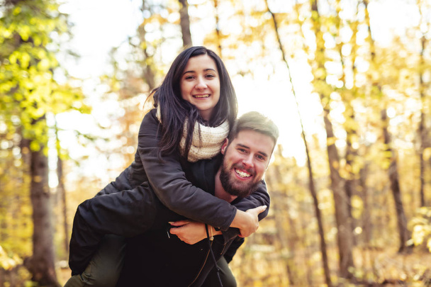 秋の公園で楽しみを持っている若いカップル - 写真・画像