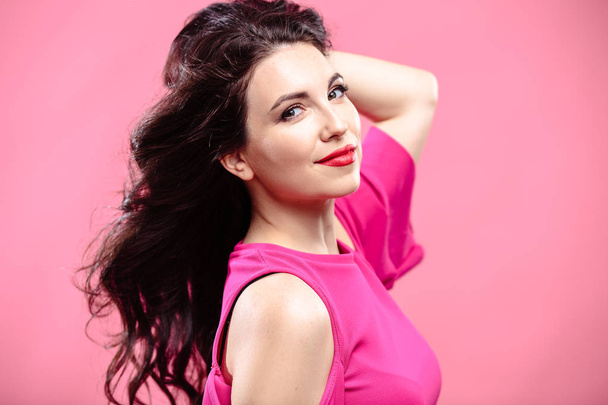 Beauty portrait of young brunette woman on a bright pink background. Model with make-up and hairstyle, closeup, fashion glamour photo - Photo, image