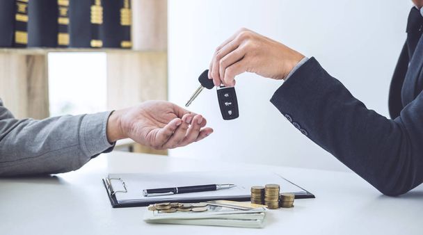 Salesman send key to customer after good deal agreement, successful car loan contract buying or selling new vehicle. - 写真・画像