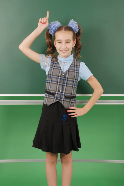 Menina bonito estudante perto de quadro negro o conceito de educação e vida escolar
 - Foto, Imagem