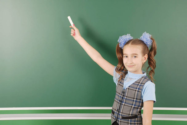 Schattig meisje schoolmeisje in de buurt van blackboard het concept van onderwijs en school leven - Foto, afbeelding