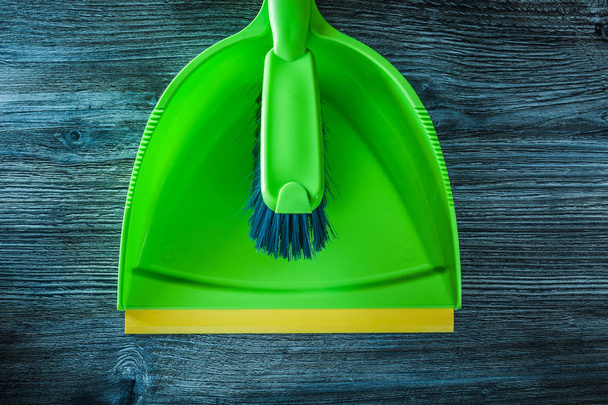 Green dustpan and brush set on wooden board. - Foto, immagini