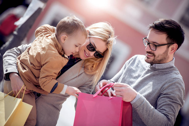 Venta, consumismo y gente concepto-familia feliz con niño pequeño y bolsas de compras en la ciudad
 - Foto, imagen