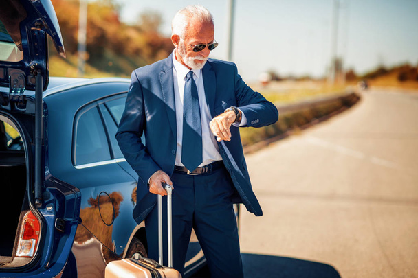 Путешествующий бизнесмен со своим багажом возле машины
. - Фото, изображение
