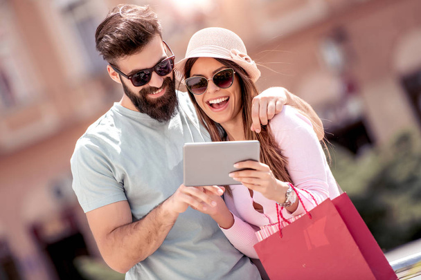 幸せな若いカップルは都市のショッピング バッグ。素敵な瞬間を一緒に過ごす. - 写真・画像