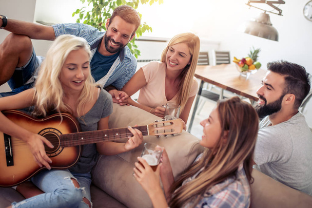 Amici che fanno festa a casa, suonano la chitarra
. - Foto, immagini