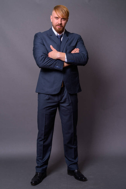 Бородатий бізнесмен з світлим волоссям на сірому фоні
 - Фото, зображення