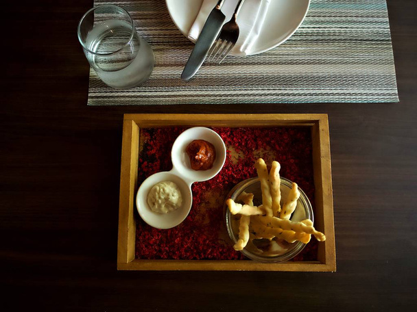Ekmek sopa çiçek ve masa gereçleri ve bir bardak su ile dekore edilmiş ahşap kutu sos ile - Fotoğraf, Görsel