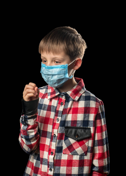 Niño enfermo con máscara médica tose sobre fondo negro
 - Foto, imagen