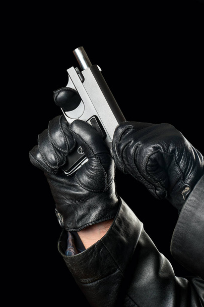 Bandit recharges gun in hands on black background - Photo, Image