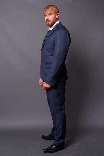 Homem de negócios barbudo com cabelo loiro contra fundo cinza - Foto, Imagem
