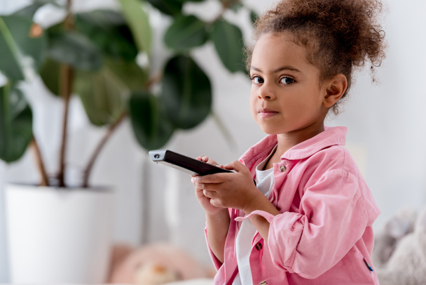  close up of African american child sitting with tv remote  - Foto, Imagem