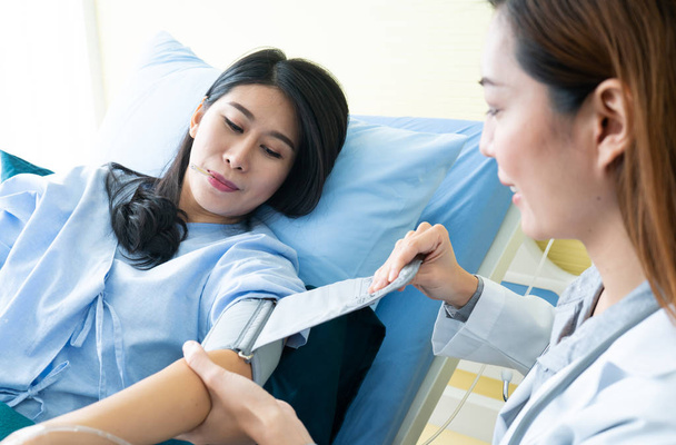 Arts met behulp van bloeddrukmeter controleren bloeddruk aan een patiënt in het ziekenhuis. - Foto, afbeelding