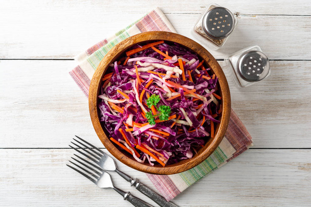 Fresh coleslaw salad with red and white cabbage and carrots in bowl on white wooden background. Top view. Copy space. - 写真・画像