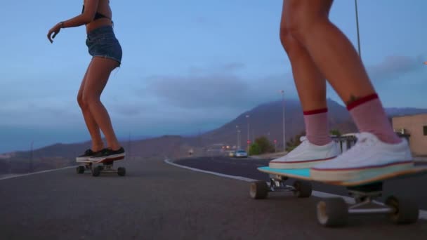 Close - up skateboard a dvě dívky, které se sází na desky z hory na pozadí skály a nebe. Zpomalený pohyb steadicam - Záběry, video
