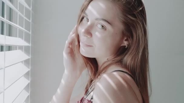 Closeup face of beautiful red hair girl in lingerie posing near the window with blinds during sunny day morning - video in slow motion - Filmagem, Vídeo