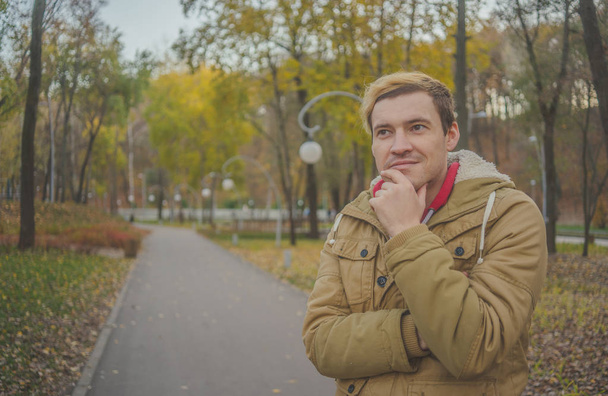 Modern handsome man in the autumn park. Seasonal fashion. Autumn style. Close up portrait of a young man on the background autumn park - Foto, imagen