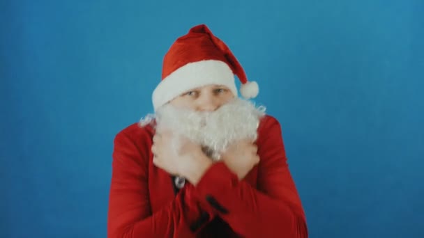 Christmas and New year, man like a Santa trembles or freezes from the cold, on blue background - Séquence, vidéo