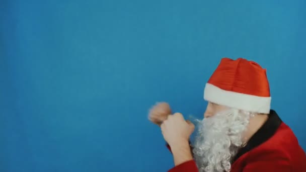 New year, man like a Santa is boxing and throws punches by his fists, Christmas 2019, on blue background - Materiaali, video