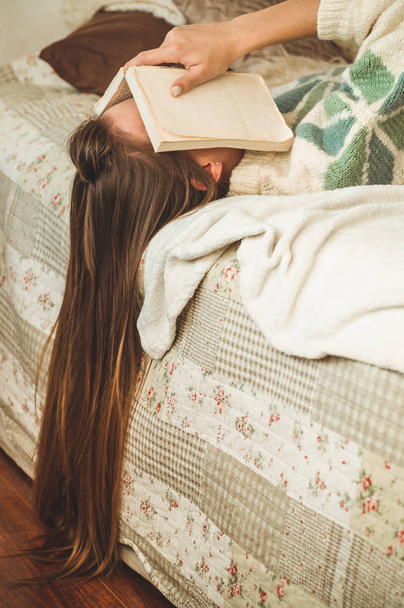 Piękna młoda kobieta, spanie na łóżku z książki, zasłaniając twarz, bo czytając książkę z przygotowania egzaminu College - Zdjęcie, obraz