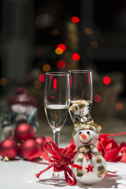 skladba pro vánoční koule, sněhulák, některé červené stužky, barevná světla a dvě sklenice šampaňského - Fotografie, Obrázek