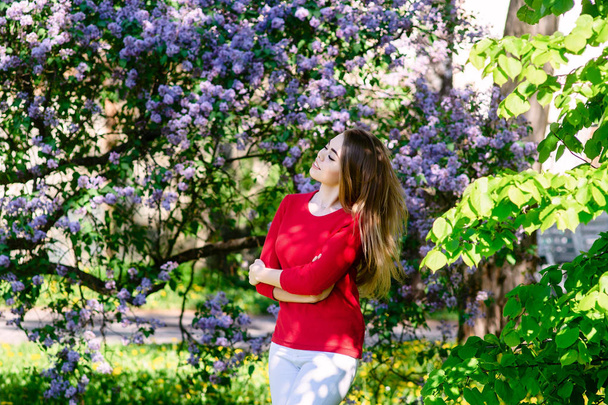Chica joven en un parque de primavera. Sobre el fondo de flor lila. Hermosa foto
. - Foto, Imagen