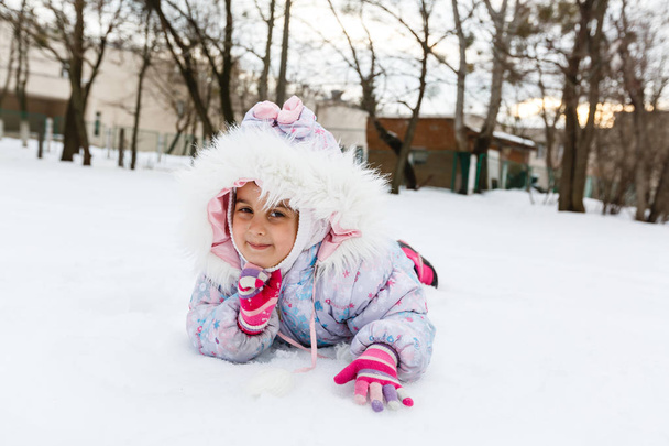 Niña con abrigo esponjoso jugando en el patio cubierto de nieve
 - Foto, Imagen
