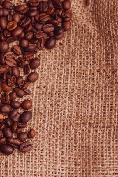 Cafe design, pictures for bars and cafes. Closeup coffee grains on burlap and brown background. - Photo, Image
