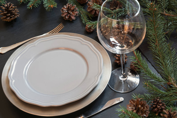 Christmas table setting with silverware and dark natural evergreen decor on black table. Close up. Holiday Centerpieces. - Foto, immagini