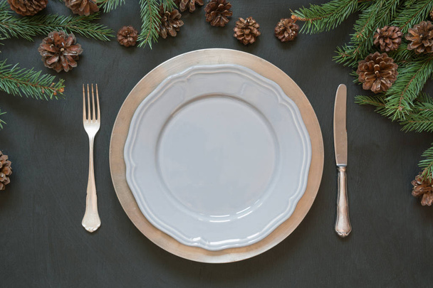 Weihnachten Tischdekoration mit Besteck und dunkel natürlichen immergrünen Dekor auf schwarzem Tisch. Ansicht von oben. Urlaubs-Herzstücke. - Foto, Bild