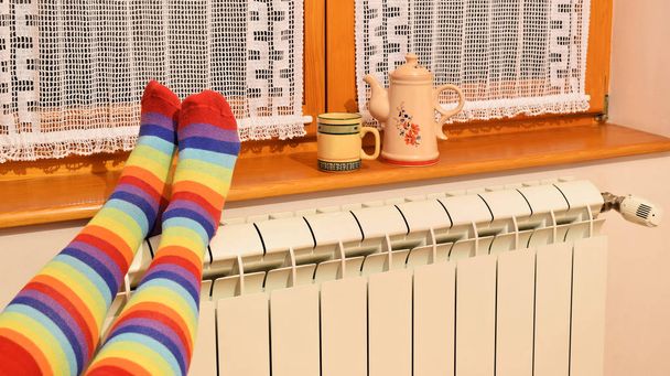 Centrale verwarming-radiator en vrouw met kleurrijke sokken in de winter - Foto, afbeelding