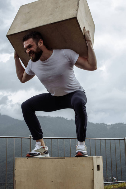 Crossfit man doing squats with weight over mountain nature background outdoor - 写真・画像