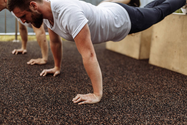 Two young athletes doing push-ups outdoors. - Foto, Imagen