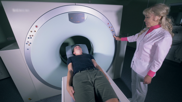 A paciente está entrando em um mecanismo de ressonância magnética sob supervisão médica feminina
 - Filmagem, Vídeo