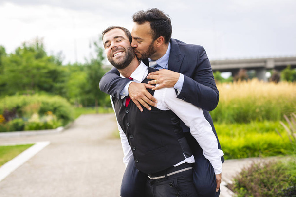 A Handsome gay male couple in the park on their wedding day - Fotoğraf, Görsel