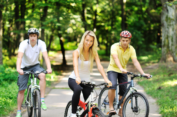 Retrato de jovem atraente na bicicleta e dois homens em blu
 - Foto, Imagem