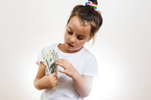 Cheerful brunette girl holding dollars on white background  - Foto, Imagen