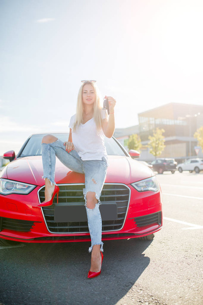 Photo of young blonde with keys standing near red car - Fotografie, Obrázek
