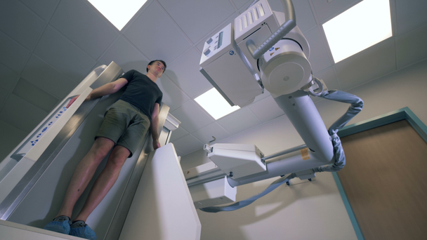 Homem adulto está de pé e sendo escaneado por uma máquina médica
 - Filmagem, Vídeo