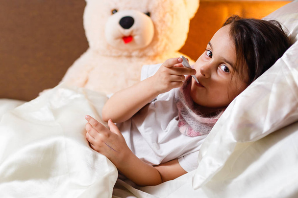 krankes kleines Mädchen in Decke gehüllt im Bett liegend  - Foto, Bild
