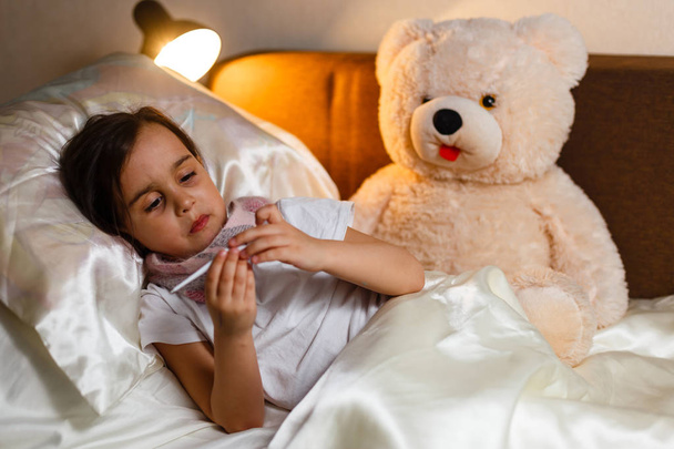 Sick little girl covered in blanket laying in bed  - Photo, image
