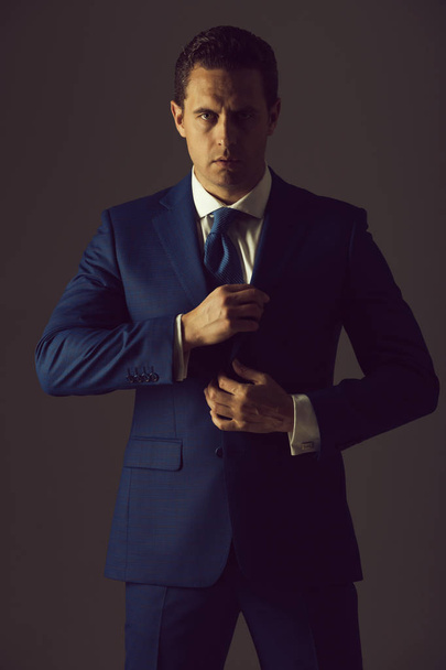 businessman with serious face holding collar in suit - Fotoğraf, Görsel