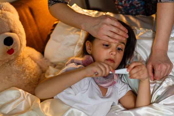 Beteg kislány borított takaró szóló ágyban  - Fotó, kép