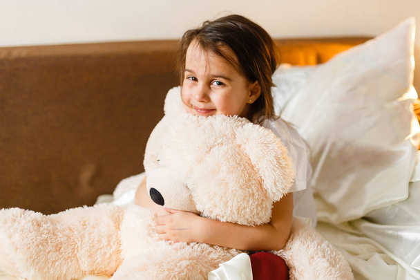 Šťastný bruneta malá holčička, která objímat medvídka - Fotografie, Obrázek