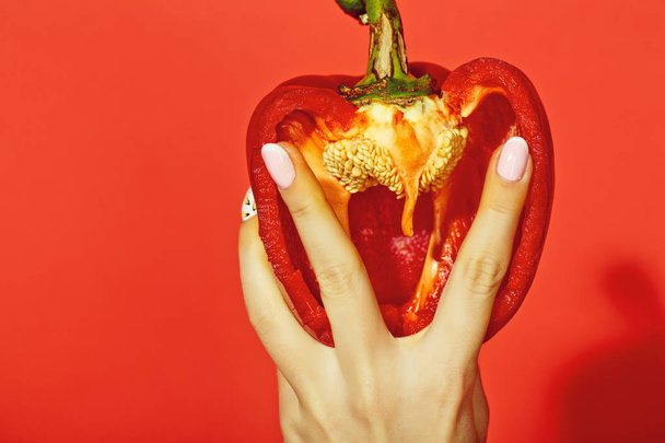 paprika in hand of girl on red background - Φωτογραφία, εικόνα
