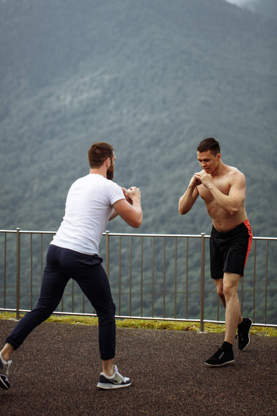 Two athletes rest after intense outdoor workout training in mountain landscape - 写真・画像